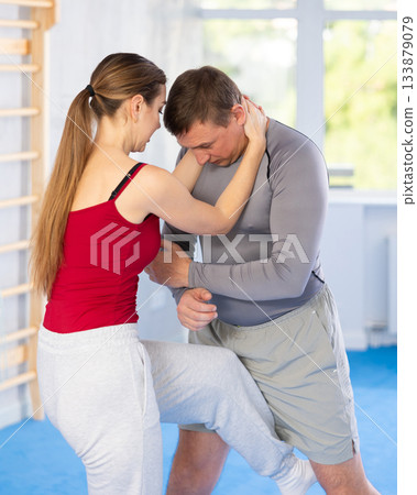 Young woman kicks attacking man - self-defense training in ring 133879079