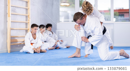 Male karate instructor training little child wearing kimono in dojo or jiu-jitsu in gym 133879081