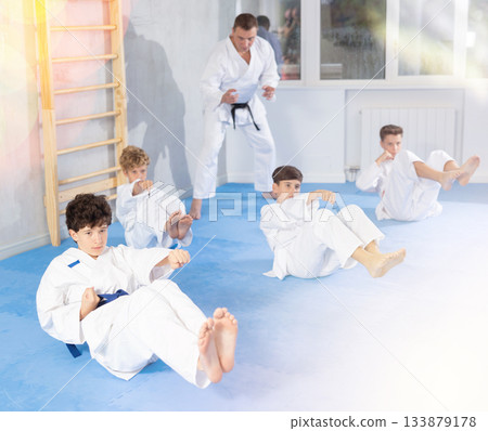 Teenagers performing core twist with simultaneous punches during martial arts training 133879178