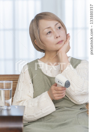 一位老婦人在客廳用體溫計測量體溫 133880357