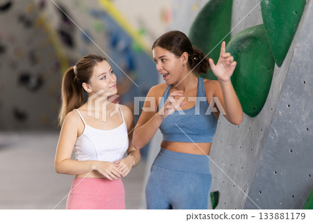 Two womens in climbing gym hall, having nice conversation before training, discussing workout plan and sharing fitness tips Two womens in climbing gym hall, having nice conversation before training, discussing workout plan and sharing fitness tips 133881179