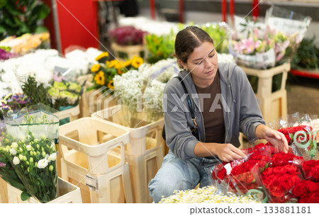 Girl salesman takes out bunch of carnation from showcase Girl salesman takes out bunch of carnation from showcase 133881181