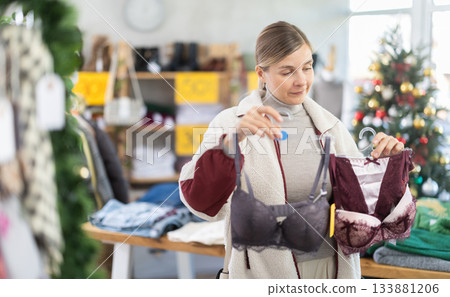 Woman client looks at products in store, choose closely at bra Woman client looks at products in store, choose closely at bra 133881206
