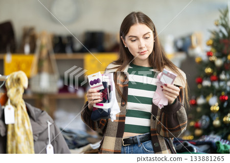 Woman choosing sets of socks in a clothing store with a Christmas tree in the background Woman choosing sets of socks in a clothing store with a Christmas tree in the background 133881265