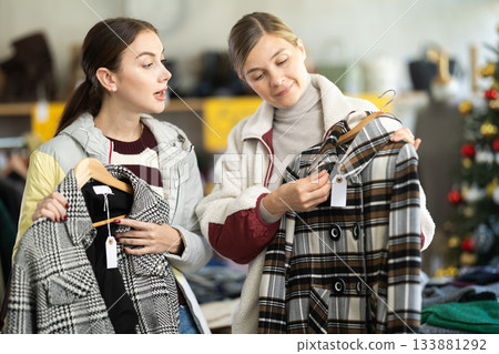Two women choosing a coat or jacket together in a clothing store for Christmas 133881292