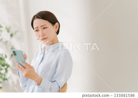 A woman in her 40s holding a smartphone 133881586