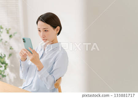 一位四十多歲的女性拿著智慧型手機 133881717