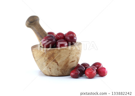 Fresh cranberries in a wooden mortar with a pestle on a white background Fresh cranberries in a wooden mortar with a pestle on a white background 133882242