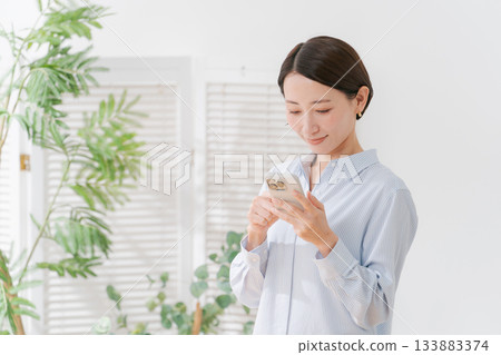 一位四十多歲的女性拿著智慧型手機 一位四十多歲的女性拿著智慧型手機 133883374