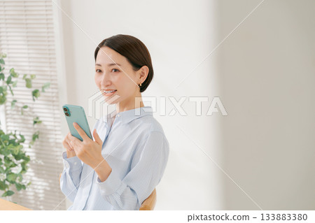 A woman in her 40s holding a smartphone A woman in her 40s holding a smartphone 133883380