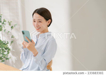 一位四十多歲的女性拿著智慧型手機 一位四十多歲的女性拿著智慧型手機 133883381