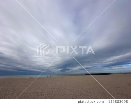 A Serene Beachscape is Beautifully Set Under Dramatic Clouds in the Sky Above the Ocean 133883698