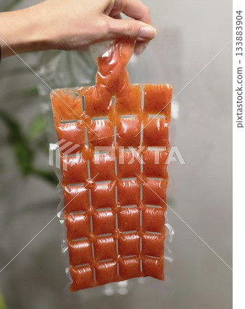Hand Holding Orange Portion Pouches for Freezing 133883904