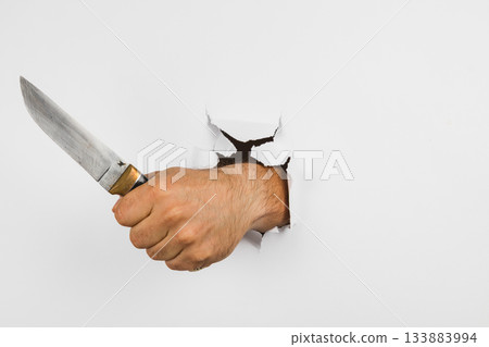 Hand with a knife breaking through a wall in a surprising scene 133883994