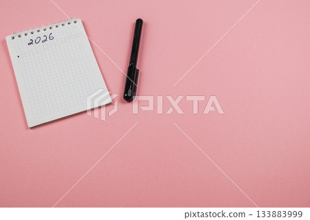Planning for the year 2026 with a notepad and pen on a pink background Planning for the year 2026 with a notepad and pen on a pink background 133883999