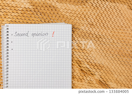 Second opinion notes on a checkered notebook placed on a woven surface Second opinion notes on a checkered notebook placed on a woven surface 133884005