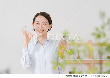 一位四十多歲的女性拿著智慧型手機 一位四十多歲的女性拿著智慧型手機 133884077
