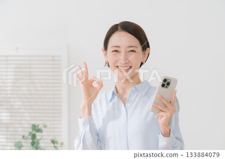A woman in her 40s holding a smartphone 133884079