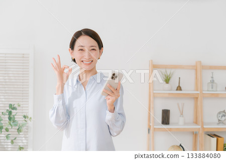 A woman in her 40s holding a smartphone A woman in her 40s holding a smartphone 133884080