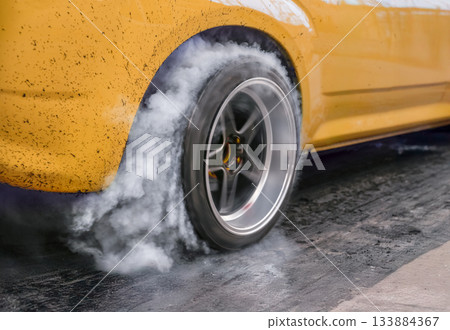 Drag racing car burns rubber off its tires in preparation for the race Drag racing car burns rubber off its tires in preparation for the race 133884367