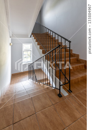 Bright Staircase Interior with Tiled Steps and Metal Railing 133884967
