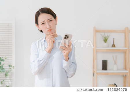 一位四十多歲的女性拿著智慧型手機 一位四十多歲的女性拿著智慧型手機 133884976