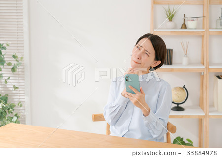 A woman in her 40s holding a smartphone A woman in her 40s holding a smartphone 133884978