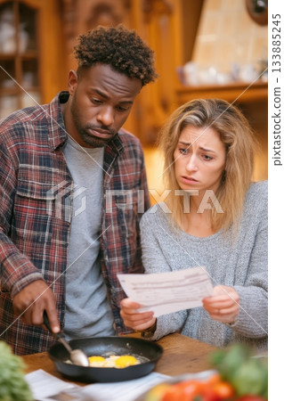A joyful couple happily cooking together in their cozy kitchen while following a recipe 133885245