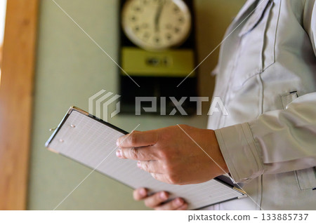 Carrying a clipboard and wearing work clothes, inspecting the interior 133885737