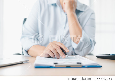 Concept of tax filing and financial documentation. Close up of businesswoman hand holding pen and pointing on tax form, symbolizing accounting, legal paperwork, budget planning and financial accuracy. Concept of tax filing and financial documentation. Close up of businesswoman hand holding pen and pointing on tax form, symbolizing accounting, legal paperwork, budget planning and financial accuracy. 133887235