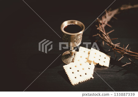 Communion bread and wine with the Holy Bible and crown of thorns, symbolizing the sacrifice of Jesus Christ, the passion, salvation and Christian faith in the Eucharist and Lord Supper. 133887339