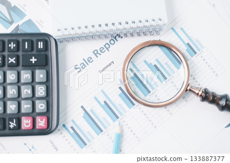 Magnifying glass with calculator and pen on financial reports with charts, graphs at office desk. Concept of business analysis, accounting audit, financial accuracy, transparency, corporate strategy. 133887377