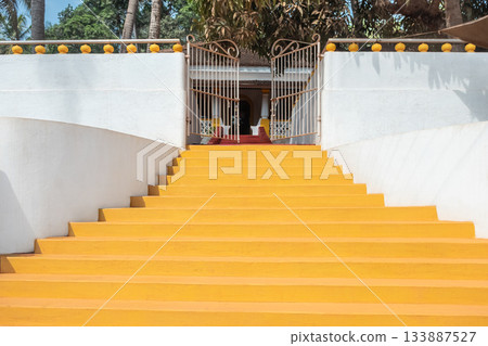 Yellow stairs to the villa. Wide stone staircase with white walls leads up to the house with garden 133887527
