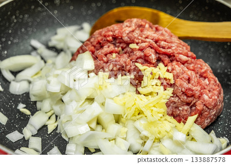 Minced meat with fresh onion on frying pan, Close up raw ground beef meat Minced meat with fresh onion on frying pan, Close up raw ground beef meat 133887578