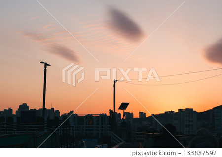 City Rooftop View of Building Silhouettes Against an Orange Sunset Sky 133887592
