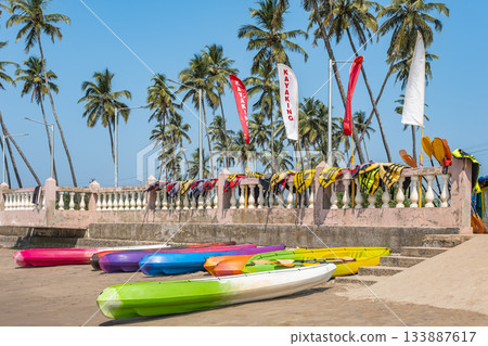 Colorful kayaks and Life jackets awaiting for tourists on the sandy beach with palm trees. 133887617