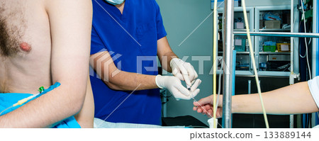 The anesthesiologist conducts and charges the syringe with anesthetics. The anesthesiologist conducts and charges the syringe with anesthetics. 133889144