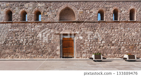 Seljuk Alaeddin Mosque Courtyard: Ancient Stone Wall, Wooden Door, and Arched Windows in Konya, Turkey. Seljuk Alaeddin Mosque Courtyard: Ancient Stone Wall, Wooden Door, and Arched Windows in Konya, Turkey. 133889476