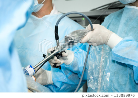 The surgeon operates with laparoscopic manipulators. 133889976