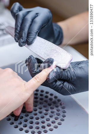Detailed view of professional manicure procedure with nail care tools and hands in focus. Detailed view of professional manicure procedure with nail care tools and hands in focus. 133890477