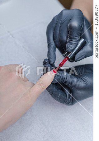 Detailed view of professional manicure procedure with nail care tools and hands in focus. Detailed view of professional manicure procedure with nail care tools and hands in focus. 133890577