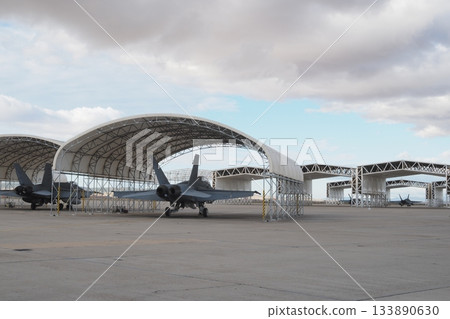 Multirole fighters parked in open hangars on wide apron Multirole fighters parked in open hangars on wide apron 133890630