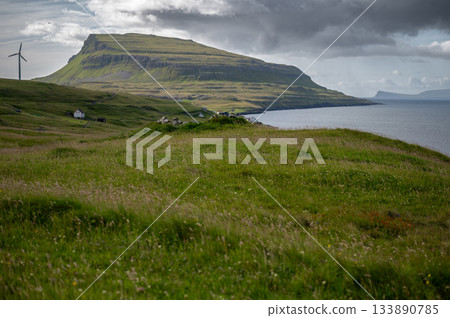 Low clouds hang over the remote Scandinavian island of Nolsoy in the Faroe Islands. Dramatic landscape of grass covered mountains and basalt columns along the coastline. High quality photo Low clouds hang over the remote Scandinavian island of Nolsoy in the Faroe Islands. Dramatic landscape of grass covered mountains and basalt columns along the coastline. High quality photo 133890785