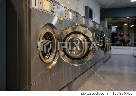 Clean row of modern washing machines in a self-service laundromat. Shared utility space for convenient and efficient laundry. 133890793