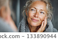 Mature woman seeing reflection feeling good about skincare 133890944