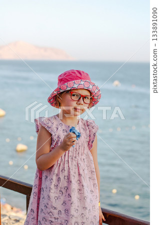 Little adorable child girl enjoying summer in the beach. Eating icecream Little adorable child girl enjoying summer in the beach. Eating icecream 133891090