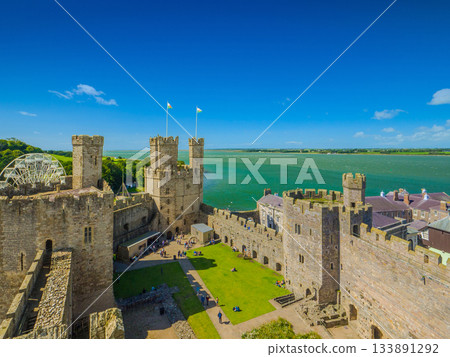 從這裡可以欣賞到卡那封城堡(世界遺產)的鷹塔和外牆全景,背景是梅奈海峽(英國威爾斯)。 從這裡可以欣賞到卡那封城堡(世界遺產)的鷹塔和外牆全景,背景是梅奈海峽(英國威爾斯)。 133891292