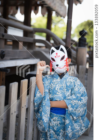 一位身穿浴衣、戴著狐狸面具的男孩,站在神社內。日本京都府 一位身穿浴衣、戴著狐狸面具的男孩,站在神社內。日本京都府 133892059