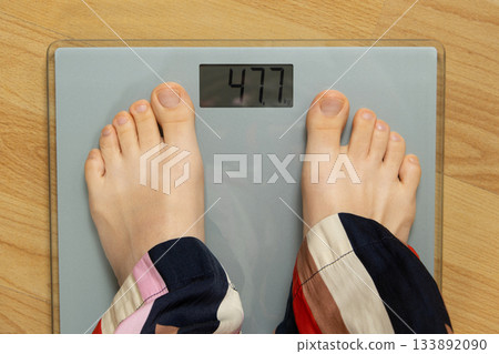 Top View of Bare Feet Standing on Modern Digital Bathroom Scales for Weighing. Top View of Bare Feet Standing on Modern Digital Bathroom Scales for Weighing. 133892090