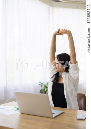 一位女士在電腦工作間隙伸展身體 133892542